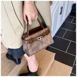 Close-up of vintage brown leather handbag with silver metal twist lock and cracked texture