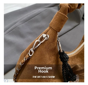 Detail of brown suede bag showing precision stitching, silver hooks and black woven handle