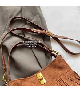 Detail of brown suede fringe shoulder bag showing vintage gold clasp and leather strap