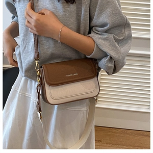 Détail du sac bandoulière bicolore avec texture litchi et deux sangles d'épaule