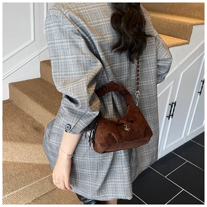 Detail of dark brown suede crescent bag featuring heart pendant and ruffled handle texture