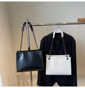 Dettaglio di borse tote trapuntate con cuciture a V e catene metalliche in nero e bianco