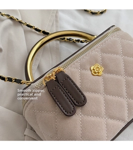 Detail of camellia logo and golden handle on quilted suede chain shoulder bag