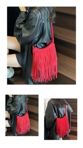 Detail of red suede shoulder bag featuring long fringe tassels and sleek crossbody strap