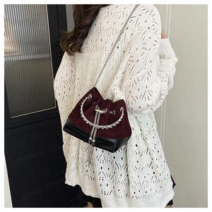 Détail du sac seau bordeaux en daim et cuir noir avec poignée en argent et franges