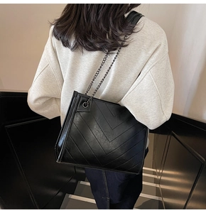 Dettaglio della borsa tote nera trapuntata con texture in pelle e tracolla a catena