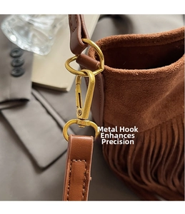 Detail of golden metal swivel hook and leather strap on a brown fringe suede bag