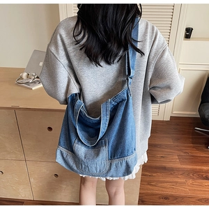 Détail d'un grand sac fourre-tout en denim avec une poche plaquée et de larges bandoulières
