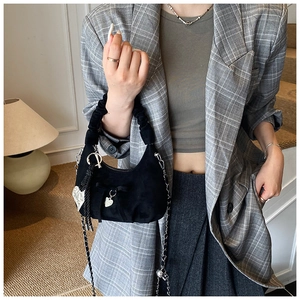Black suede crescent bag with bow decor, metal chain, and heart charm detail