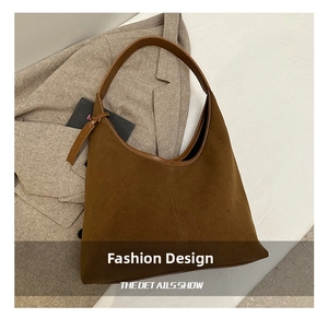Détail du sac hobo en daim marron avec bandoulière en cuir sur fond de blazer gris clair
