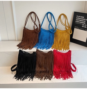 Selection of suede fringe crossbody bags in six vibrant colors displayed on white steps