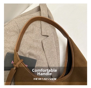 Détails d'un sac cabas en daim marron posé sur une veste de costume grise