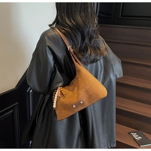 Détail d'un sac hobo en daim marron avec perles en bois vintage et pompon chic