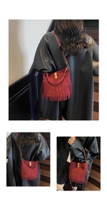Macro detail of burgundy suede crossbody bag with long tassels and gold turn-lock closure