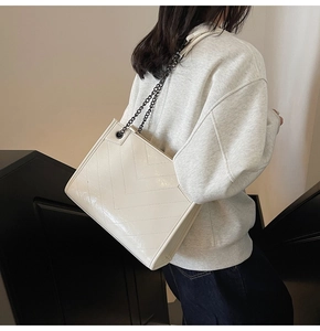 Dettaglio della borsa tote bianco crema con trapuntatura a V e catena in metallo