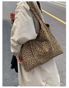 Detail view of leopard print tote bag with side pocket shown on a khaki trench coat