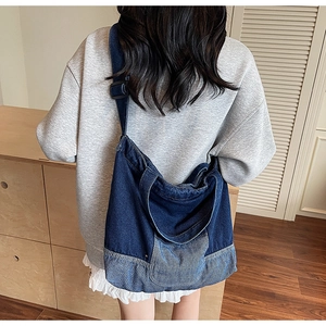 Détail d'un sac cabas en denim bleu avec finition dégradée lavée et bandoulière réglable