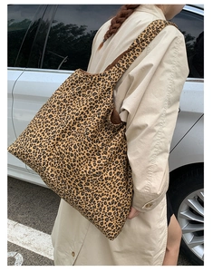 Close-up of leopard print tote bag with wide shoulder strap in outdoor urban setting