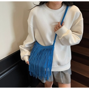 Macro detail of vibrant blue suede fringe crossbody bag with long tassel accents