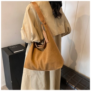 Détail du sac hobo en daim caramel montrant la bandoulière large et la texture
