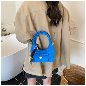 Detail view of bright blue suede crescent bag with bow decoration and chain strap