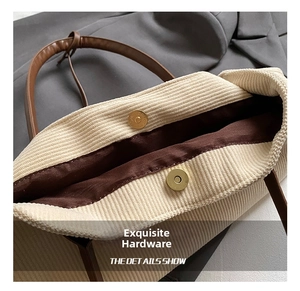 Detail of beige corduroy tote with magnetic gold snap closure and brown leather strap