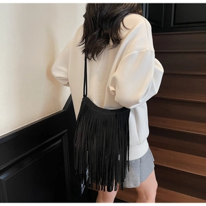 Detail of bohemian black suede shoulder bag featuring long fringe tassels and retro style