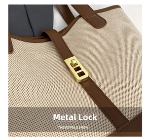 Close-up of golden hardware turn-lock on a textured canvas and brown leather tote bag