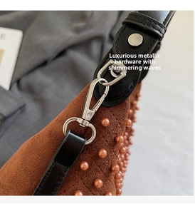 Detail of silver metallic hardware and rivets on brown suede texture shoulder bag
