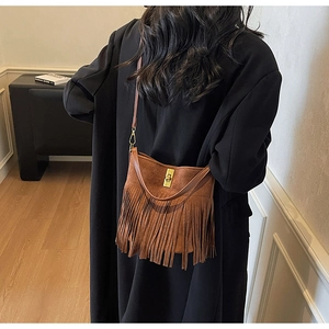 Détail du sac à bandoulière en daim marron à franges avec fermoir doré sur mannequin