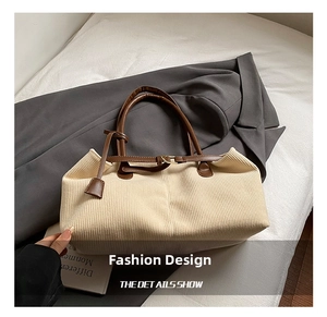 Detail showing beige corduroy texture and dark brown leather handles on a tote bag