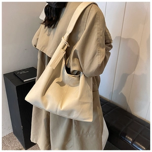 Grand sac hobo beige chic porté avec un trench-coat d'automne élégant et moderne