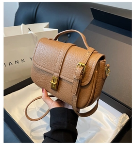Detail of vintage brown lychee textured leather bag with gold hardware and packaging
