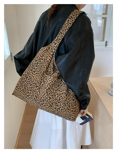 Detail of leopard print tote bag with contrasting blue interior lining shown on shoulder