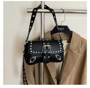 Detail of black punk shoulder bag with silver rivets and metal buckle on brown blazer