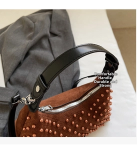 Detail of brown suede handbag with bronze rivets and durable black leather handle