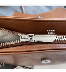 Detalle de la cremallera de metal plateado y la textura de cuero marrón del bolso de mano