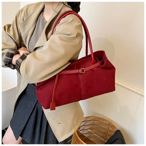 Detalle del bolso tote de pana roja mostrando la tela texturizada y la correa de cuero