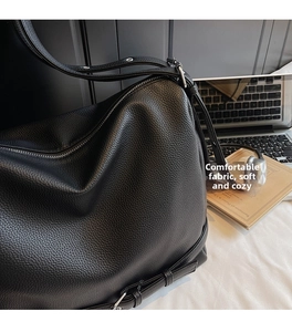 Macro detail of black litchi grain leather tote bag with silver metal zipper closure