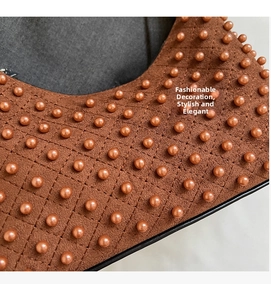 Macro shot of brown suede dumpling bag with quilted texture and orange pearl accents
