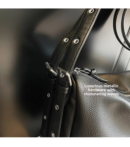 Macro detail of black litchi grain leather bag with polished silver buckle and metal eyelets