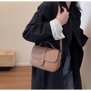 Close-up of brown litchi grain leather crossbody bag with elegant gold metal twist lock