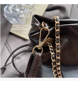 Detail of glossy leather bucket bag showing premium gold-tone metal chain and hooks