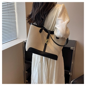 Detail of canvas tote bag showing the gold B-buckle closure and leather trim