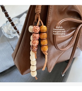 Detalle de bolso bandolera de cuero marrón con colgantes de madera étnicos y cadena metálica