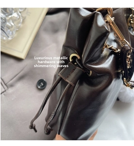 Detail of dark brown glossy leather bucket bag with gold eyelets and drawstring closure