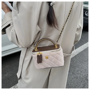 Detail of elegant beige quilted box bag with a golden rose clasp and chain strap