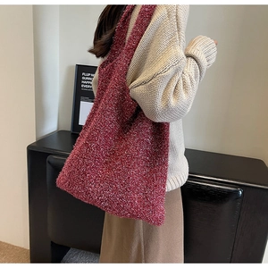 Close-up of a burgundy knit tote bag with gold glitter thread on a model's shoulder