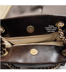 Detail view of strong magnetic closure and gold chain strap on brown leather bucket bag