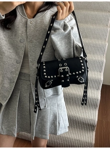 Detail shot of vintage punk shoulder bag with silver rivets and metal buckle strap